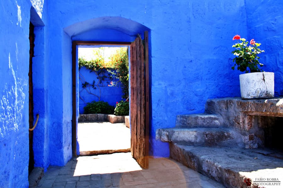 Ruelle étroite avec des murs rouges et des plantes fleuries à Arequipa